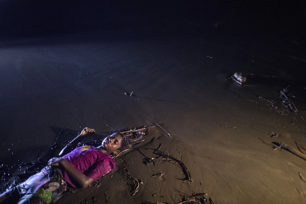 PATUWARTEK, INANI BEACH, BANGLADESH - SEPTEMBER 28: (EDITORS NOTE: Image depicts death.) The body of a Rohingya woman lays on a beach washed up after a boat sunk in rough seas off the coast of Bangladesh carrying over 100 people September 28 close to Patuwartek, Inani beach, Bangladesh. Seventeen survivors were found along with the bodies of 15 women and children. Over 500 Rohingya refugees have fled into Bangladesh since late August during the outbreak of violence in Rakhine state as Myanmar's de facto leader Aung San Suu Kyi downplayed the crisis during a speech in Myanmar this week faces and defended the security forces while criticism on her handling of the Rohingya crisis grows. Bangladesh's prime minister, Sheikh Hasina, spoke at the United Nations General Assembly last week, focusing on the humanitarian challenges of hosting the minority Muslim group who currently lack food, medical services, and toilets, while new satellite images from Myanmar's Rakhine state continue to show smoke rising from Rohingya villages.  (Photo by Paula Bronstein/Getty Images)