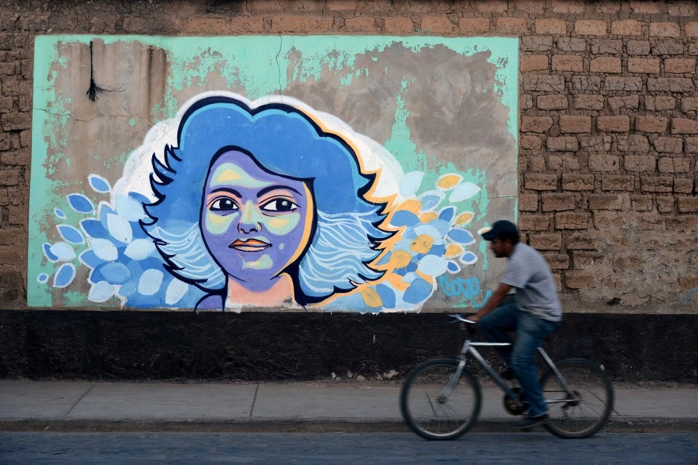 TOPSHOT - A man rides a bike past graffiti of Honduran indigenous environmentalist Berta Caceres a year after her murder, in La Esperanza, 180 km west of Tegucigalpa, on March 2, 2017. Caceres, an organizer of the Lenca people, the largest native group in Honduras, was murdered on March 3, 2016 in this city. / AFP PHOTO / ORLANDO SIERRA (Photo credit should read ORLANDO SIERRA/AFP/Getty Images)