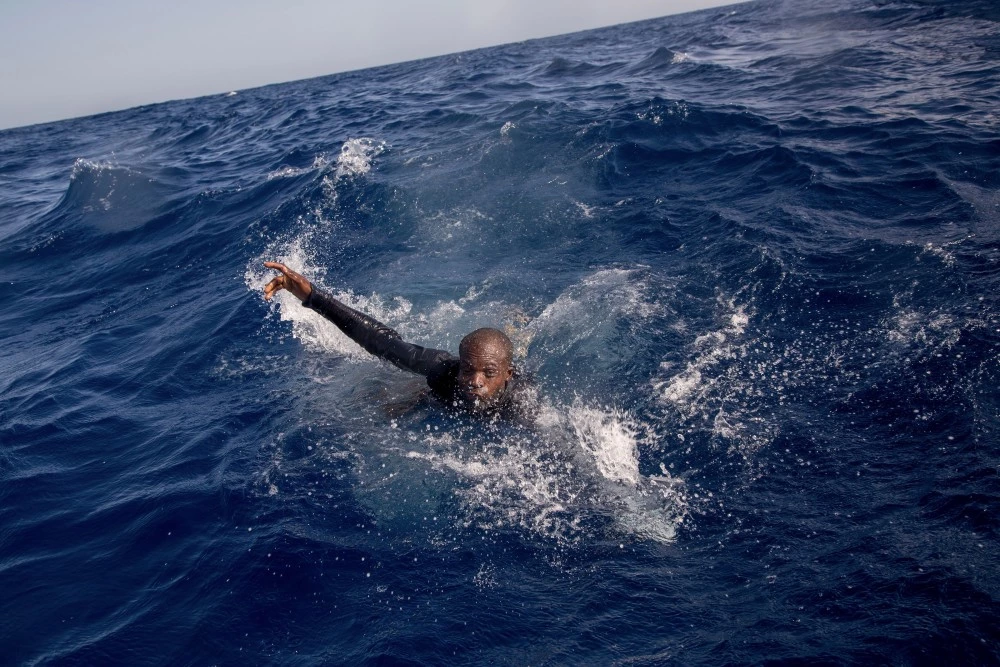 A migrant tries to board a boat of the German NGO Sea-Watch in the Mediterranean Sea on November 6, 2017.During a shipwreck, five people died, including a newborn child. According to the German NGO Sea-Watch, which has saved 58 migrants, the violent behavior of the Libyan coast guard caused the death of five persons. / AFP PHOTO / Alessio Paduano (Photo credit should read ALESSIO PADUANO/AFP/Getty Images)