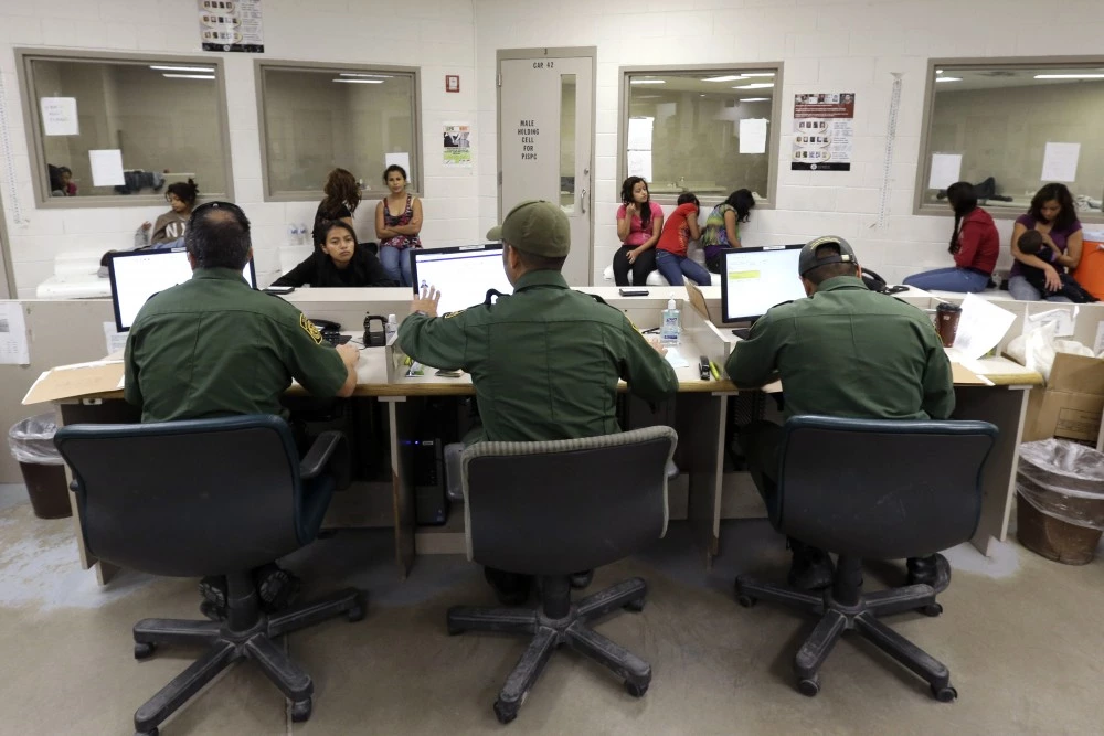 FILE - This June 18, 2014 file photo shows U.S. Customs and Border Protection agents working at a processing facility in Brownsville,Texas. Immigration courts are speeding up hearings for the tens of thousands of Central American children caught on the U.S. border after criticism that the backlogged system is letting immigrants stay in the country for years while waiting for their cases to be heard. (AP Photo/Eric Gay, Pool)