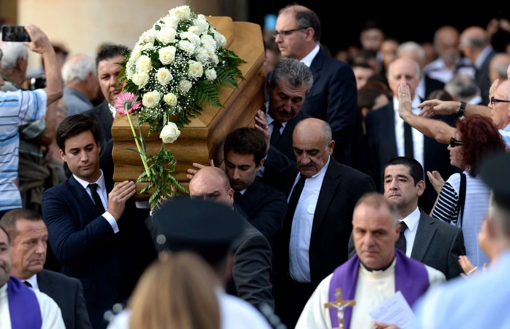TOPSHOT - The sons of murdered journalist Daphne Caruana Galizia carry the coffin of their mother out of the church in Mosta, on November 3, 2017, after her funeral ceremony. The anti-corruption campaigner will be laid to rest after a service in Mosta, close to the site where the blogger was blown up in a car bombing in an October 16 attack which made headlines around the world. Caruana Galizia, 53, had made repeated and detailed corruption allegations for years against Prime Minister Joseph Muscat's inner circle and had recently turned her investigative scrutiny on the opposition as well. / AFP PHOTO / Matthew Mirabelli / Malta OUT (Photo credit should read MATTHEW MIRABELLI/AFP/Getty Images)