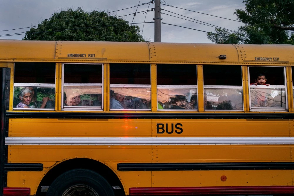 April 2017, El Salvador, San Salvador. Children look out the window at the scene of what police say was a gang assassination of a young women waiting for her daughter to get out of school.(Natalie Keyssar)