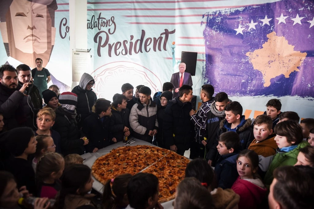 Children gather around a pizza at a restaurant near the town of Ferizaj on January 28, 2017, where  45 pizzas were given for free in honor to the new elected  President of the United States of America. / AFP / Armend NIMANI        (Photo credit should read ARMEND NIMANI/AFP/Getty Images)