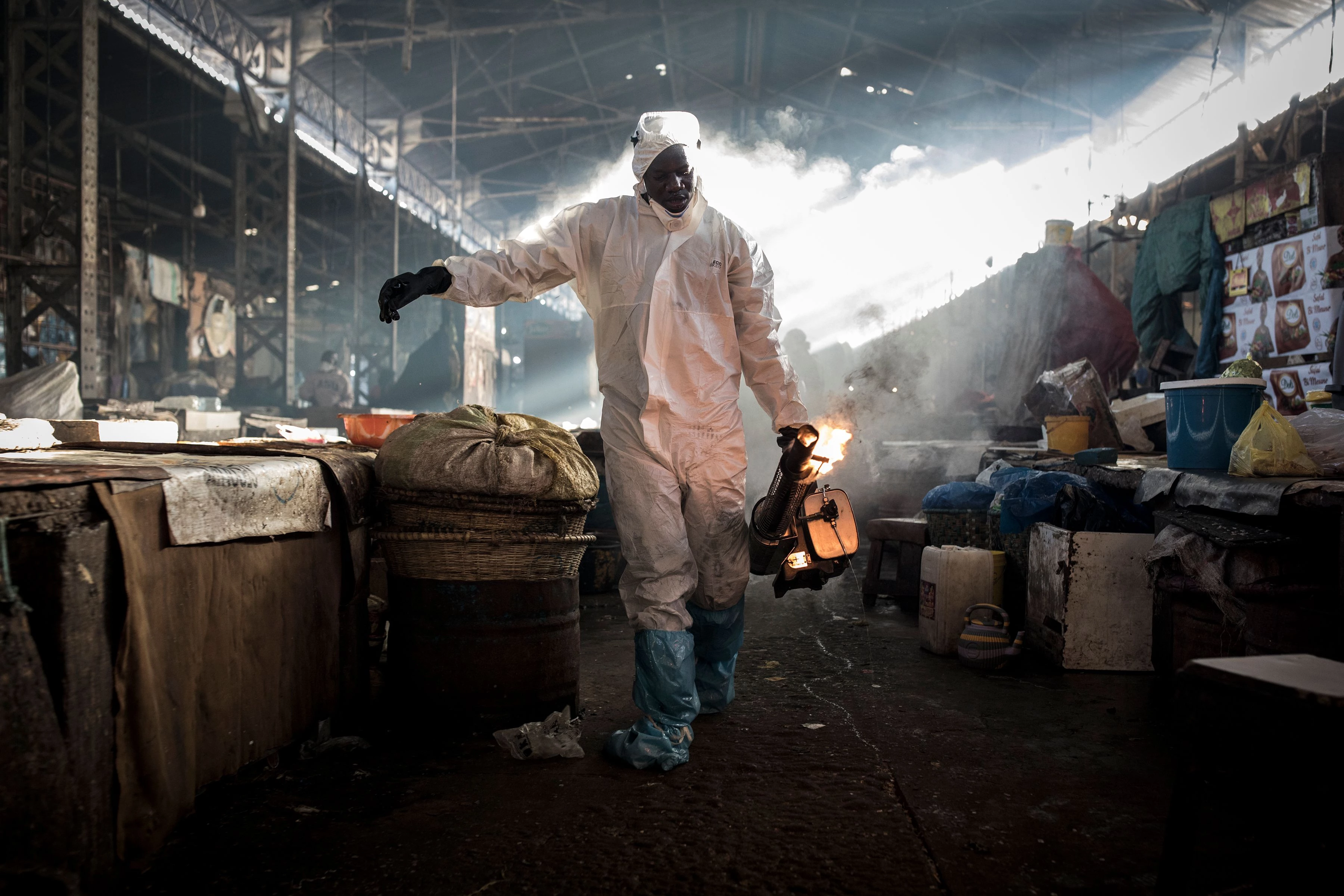 Um trabalhador municipal vestindo traje de proteção desinfeta um mercado no bairro de Medina, em Dakar, Senegal, em 22 de março de 2020.