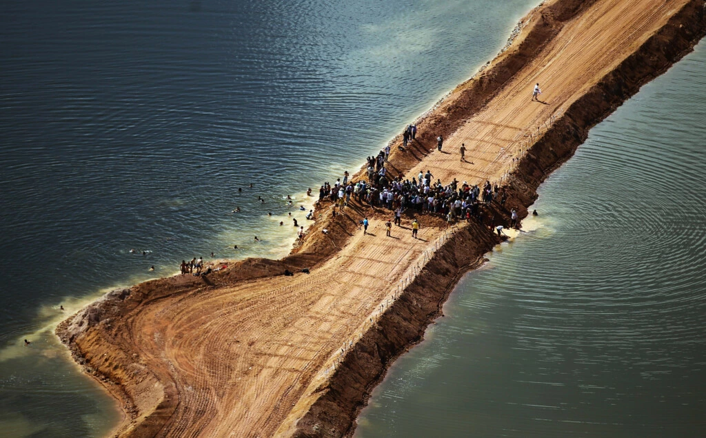 NEAR ALTAMIRA, BRAZIL - JUNE 15:  Residents who are being displaced by the Belo Monte dam and supporters stand atop a temporary earthen dam at the construction site after removing a strip of earth to restore the flow of the Xingu River as a protest against the construction on June 15, 2012 near Altamira, Brazil. Belo Monte will be the world’s third-largest hydroelectric project and will displace up to 20,000 people while diverting the Xingu River and flooding as much as 230 square miles of rainforest. The controversial project is one of around 60 hydroelectric projects Brazil has planned in the Amazon to generate electricity for its rapidly expanding economy. While environmentalists and indigenous groups oppose the dam, many Brazilians support the project. The Brazilian Amazon, home to 60 percent of the world’s largest forest and 20 percent of the Earth’s oxygen, remains threatened by the rapid development of the country. The area is currently populated by over 20 million people and is challenged by deforestation, agriculture, mining, a governmental dam building spree, illegal land speculation including the occupation of forest reserves and indigenous land and other issues. Over 100 heads of state and tens of thousands of participants and protesters will descend on Rio de Janeiro, Brazil, later this month for the Rio+20 United Nations Conference on Sustainable Development or ‘Earth Summit’. Host Brazil is caught up in its own dilemma between accelerated growth and environmental preservation.  (Photo by Mario Tama/Getty Images)