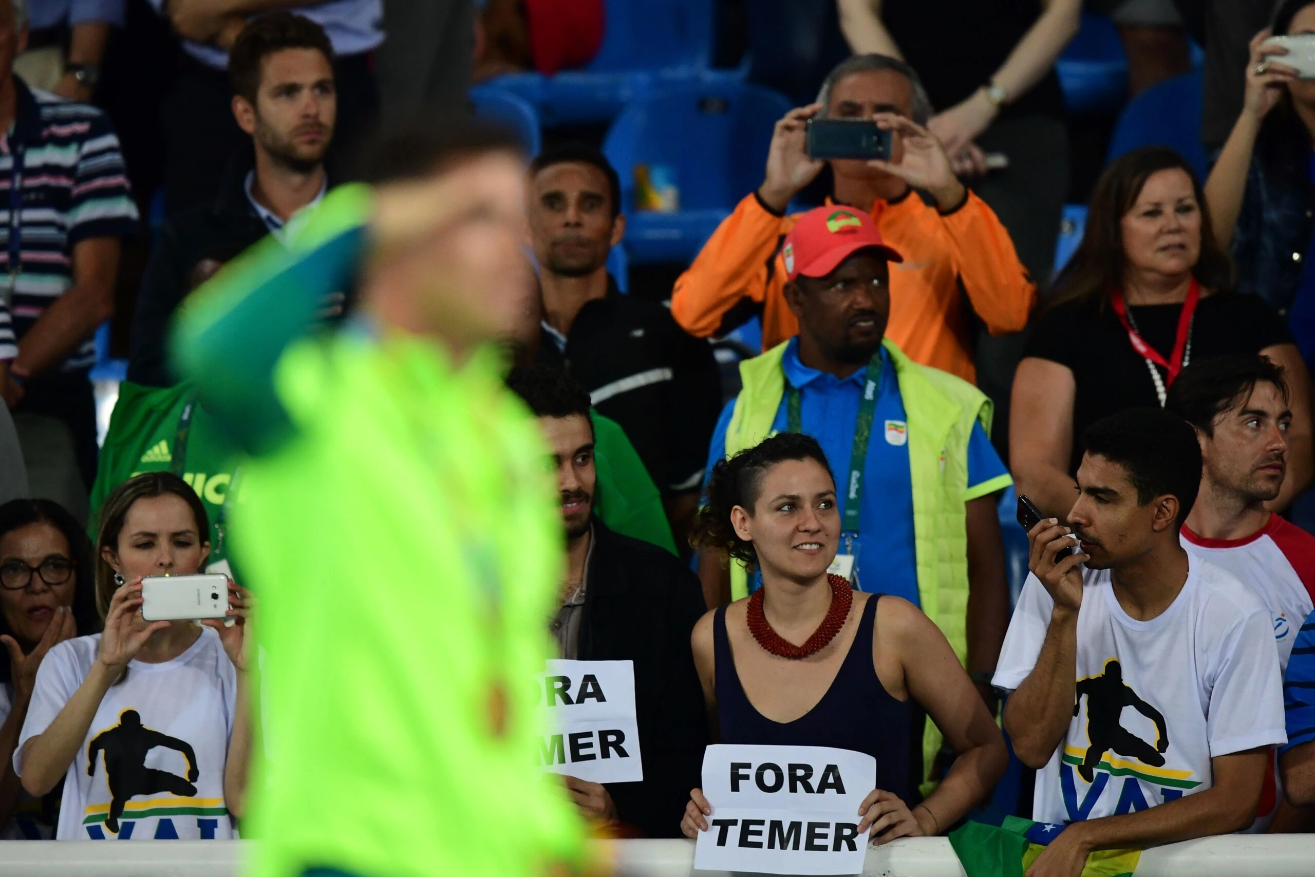 Gold medallist Brazil's Thiago Braz Da Silva (L) celebrates on the podium as people hold a banner reading "out with Temer" (Brazil's interim president Michel Temer) at the medal ceremony for the men's pole vault during the athletics event at the Rio 2016 Olympic Games at the Olympic Stadium in Rio de Janeiro on August 16, 2016. / AFP / FRANCK FIFE        (Photo credit should read FRANCK FIFE/AFP/Getty Images)