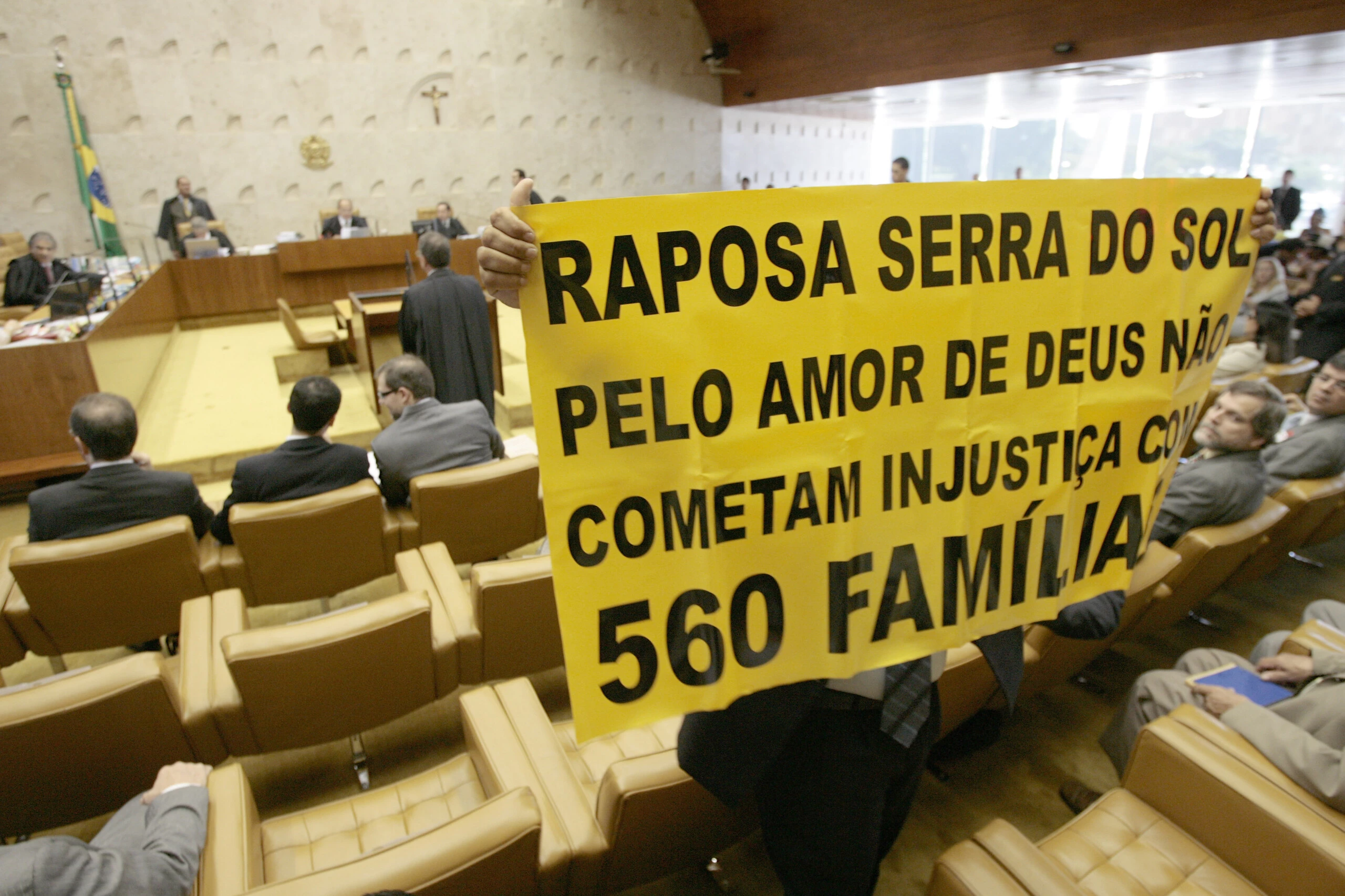 A representative of a group of farmers who oppose a resolution of Brazil's Supreme Court, confirming that the Raposa Serra do Sol reservation in northern Brazil must remain intact, holds a sign during a court's session in Brasilia, Thursday, March 19, 2009. The court ruled Thursday that the reservation must remain intact, a ruling seen as bolstering indigenous rights, and which sets an important precedent for laying out and protecting the boundaries for many Indian reserves in Brazil.The sign reads in Portuguese: "Raposa Serra do Sol, for the love of God don't commit injustice for 560 families".(AP Photo/Eraldo Peres)