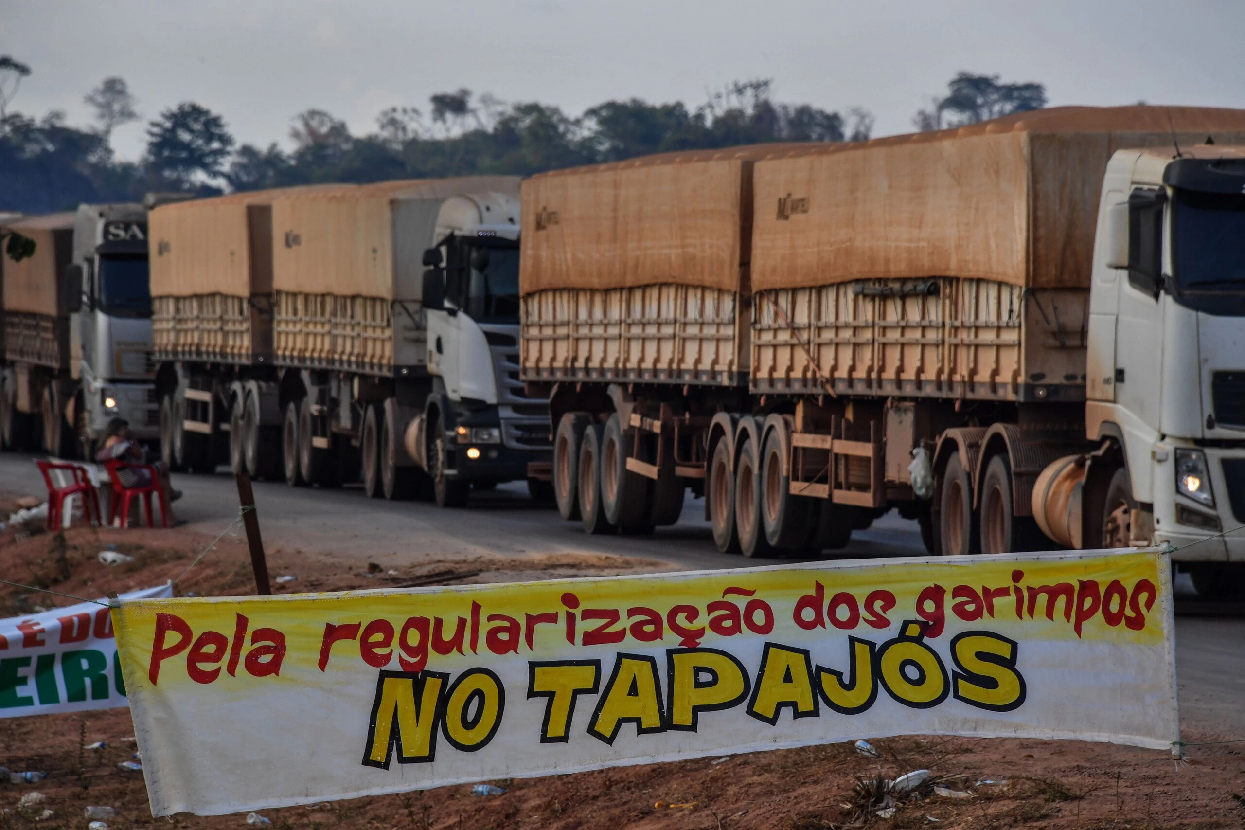 Truckers line up behind a banner reading "For the regularization of garimpos (illegal mines) in Tapajos", referring to the Tapajos River, on the BR 163 highway, blocked by "garimpeiros" -illegal gold miners- during a protest in Morais Almeida, Itaituba, Para state, Brazil, on September 13, 2019. - Members of an indigenous tribe in the Amazon in northern Brazil on Friday called for wildcat miners to be allowed to prospect for gold on their land, saying it was a source of income. (Photo by NELSON ALMEIDA / AFP)        (Photo credit should read NELSON ALMEIDA/AFP/Getty Images)