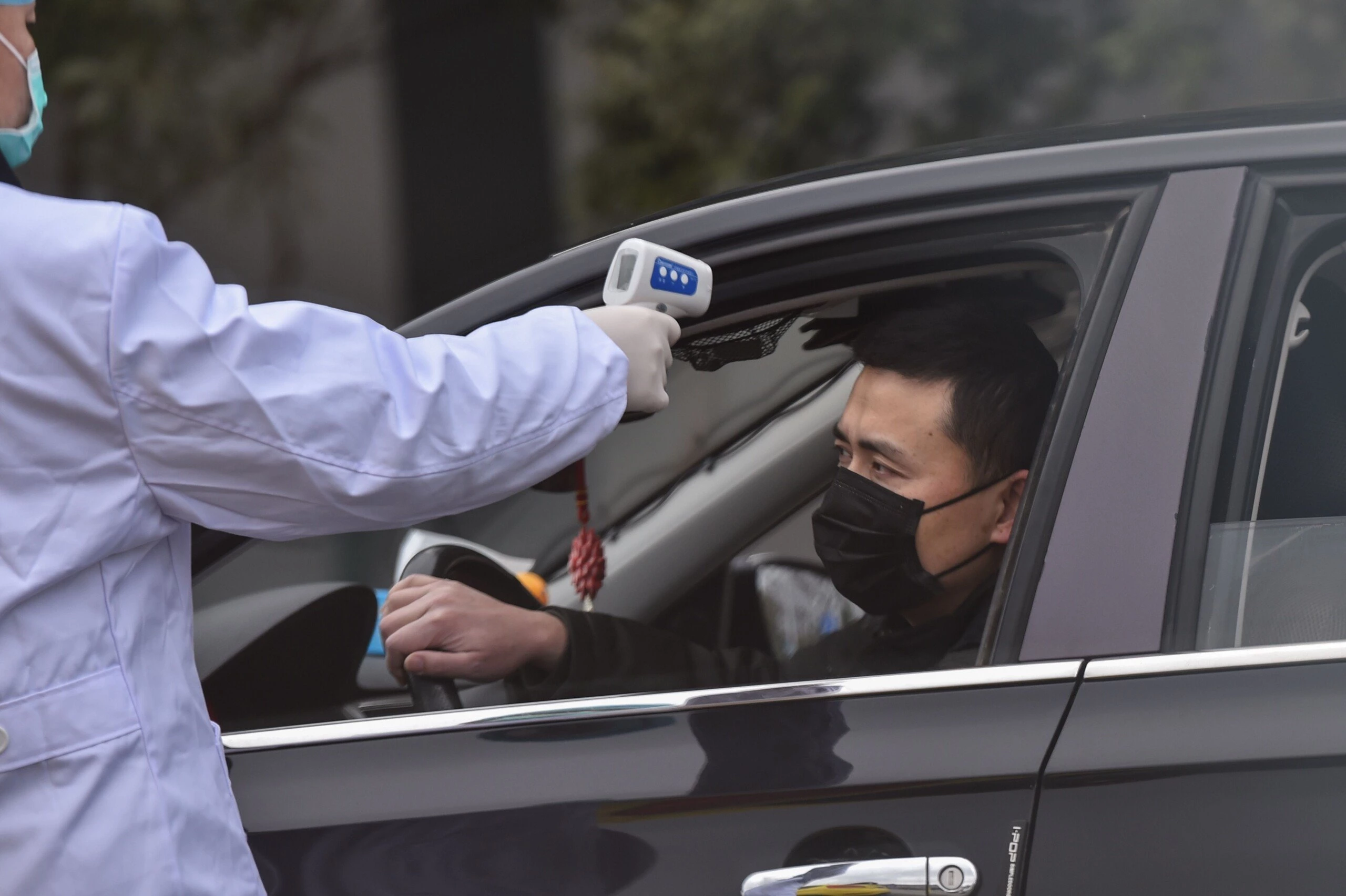 Policial mede a temperatura de motorista nas ruas de Wuhan, capital da província de Hubei, nesta segunda-feira, 27 de janeiro.