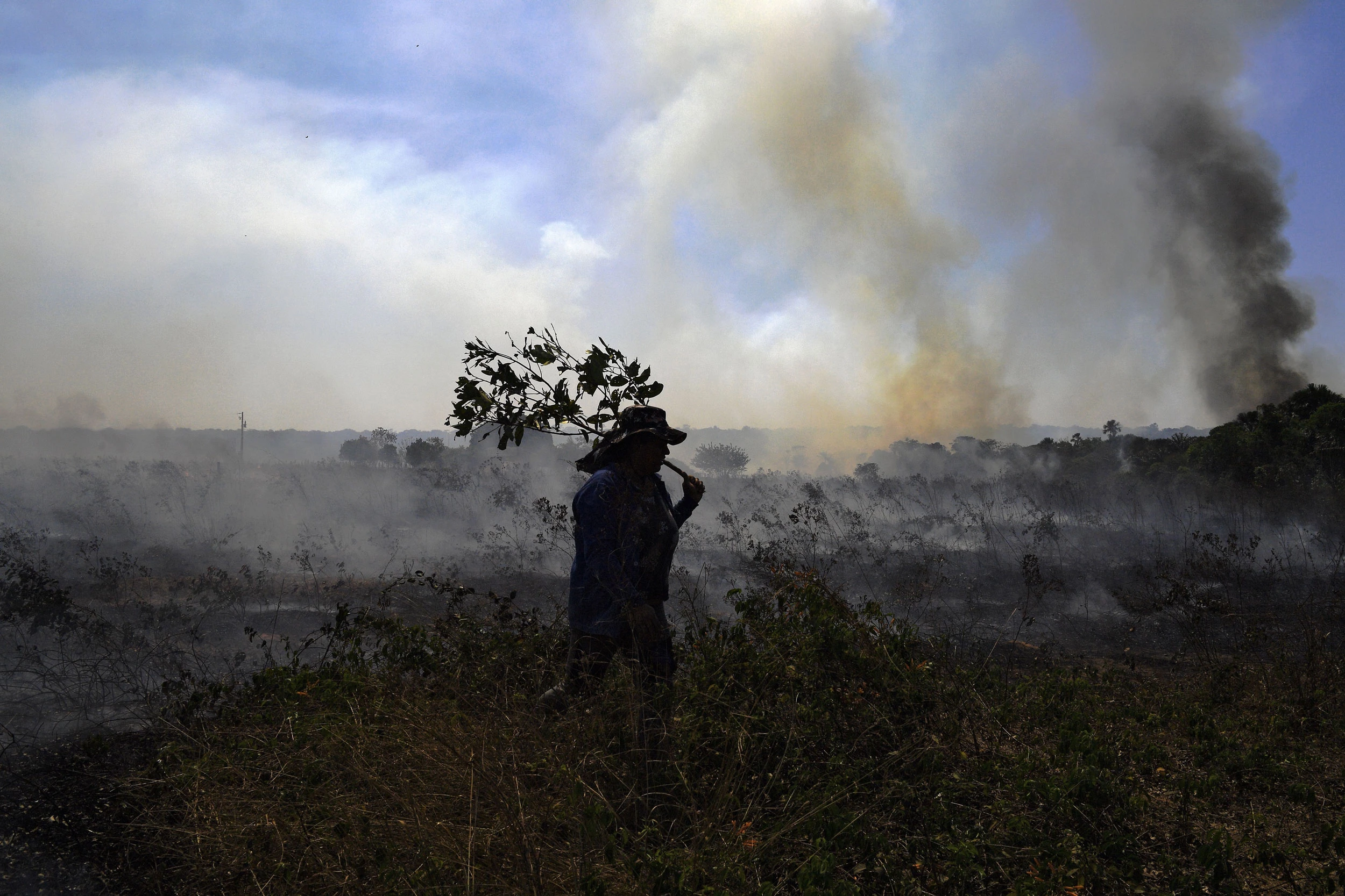 TOPSHOT - A farm worker tries to put out an illegal fire which burned part of the Amazon rainforest reserve and was spreading to their land north of Sinop, in Mato Grosso State, Brazil, on August 10, 2020. (Photo by Carl DE SOUZA / AFP) (Photo by CARL DE SOUZA/AFP via Getty Images)