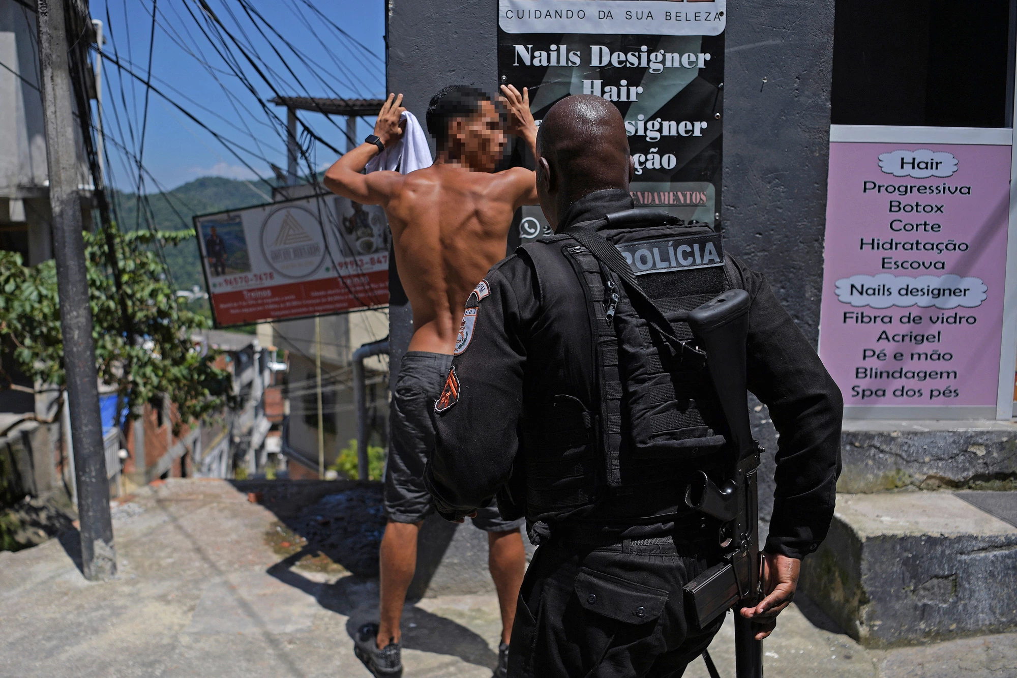 A member of the Brazilian Military Police stops a suspect during a large scale operation against drug trafficking and militias, to occupy and secure parts of the Morro do Banco favela in Rio de Janeiro, Brazil, on January 20, 2022. (Photo by CARL DE SOUZA / AFP) (Photo by CARL DE SOUZA/AFP via Getty Images)
