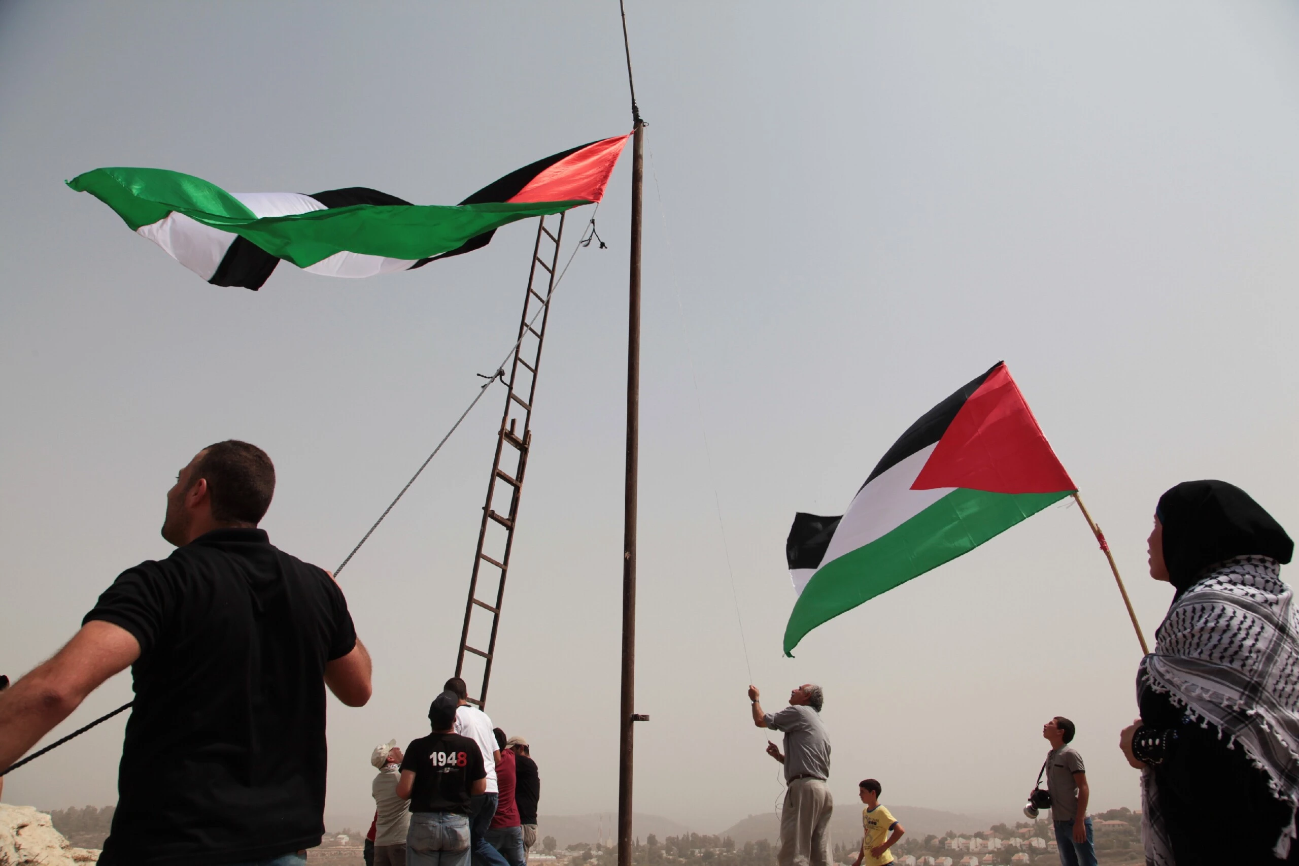 Manifestantes palestinos levantam uma grande bandeira da Palestina em Nabi Saleh em 11 de setembro de 2015.