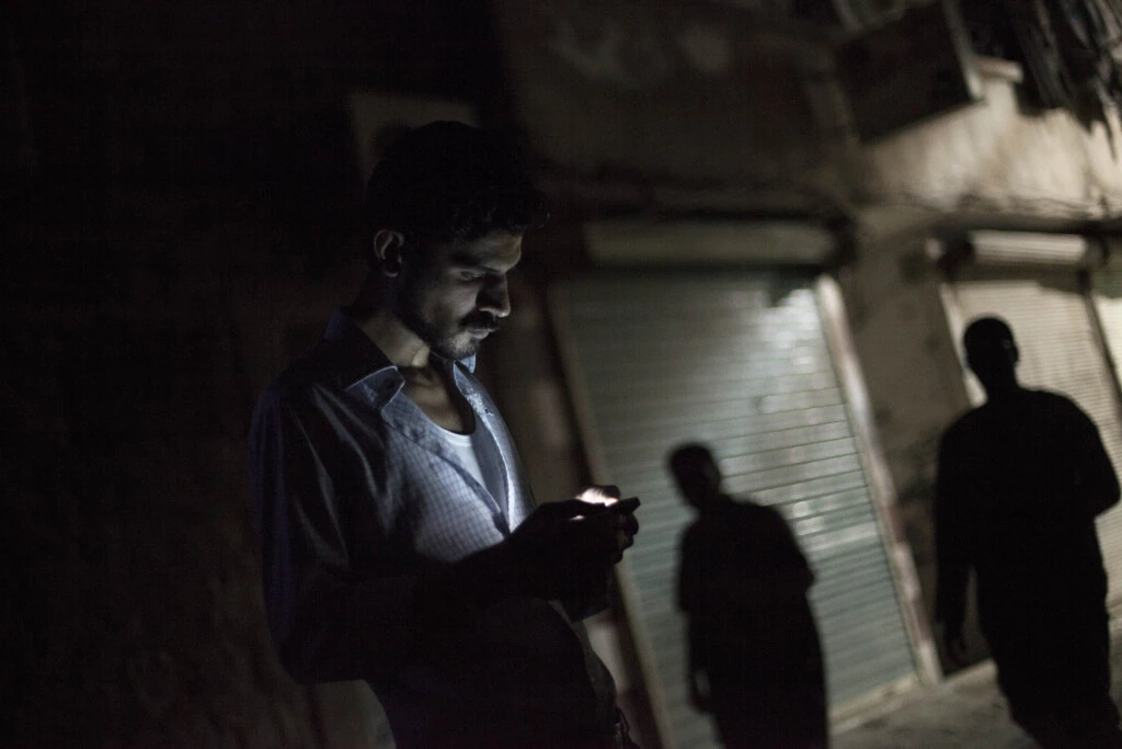 Homem sírio olha para o seu celular no bairro de Bustan al-Qasr, em Aleppo, Síria, em 21 de setembro de 2012.