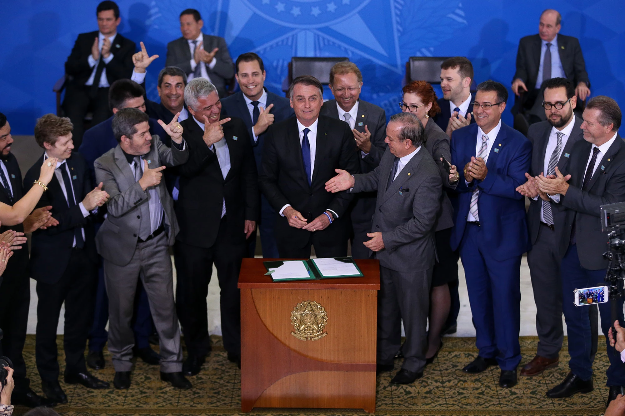 O presidente Jair Bolsonaro, acompanhado de deputados favoráveis à projetos de flexibilização do controle de armas, durante assinatura de decreto presidencial que flexibiliza regras para atiradores esportivos, caçadores e colecionadores de armas.