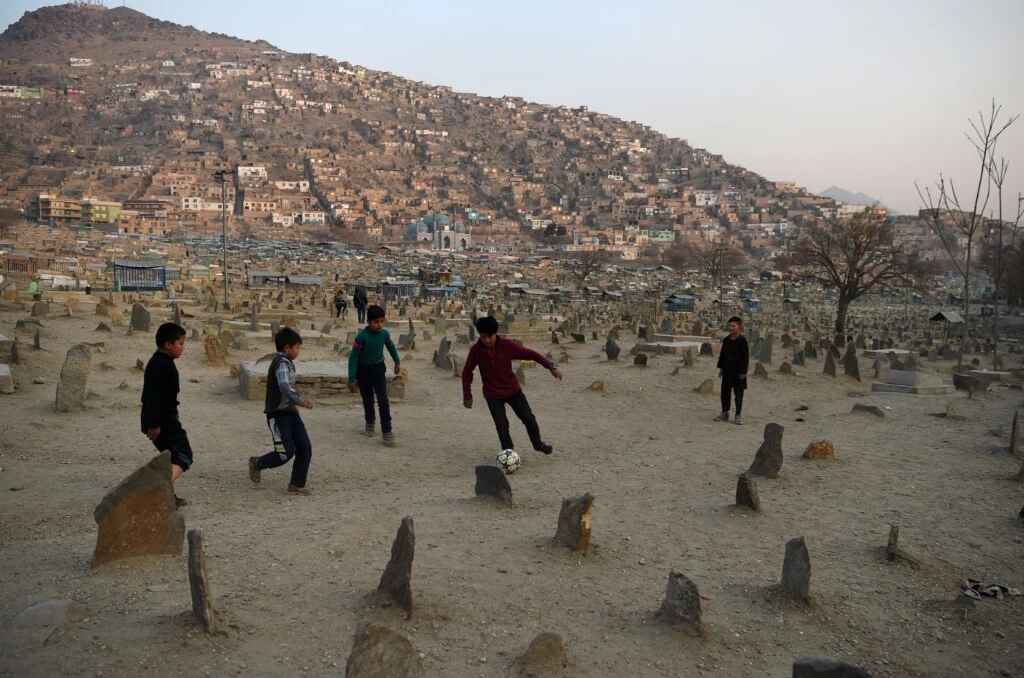 Meninos afegãos jogam futebol no cemitério de Kart-e-Sakhi, em Cabul, em 30 de dezembro de 2018.