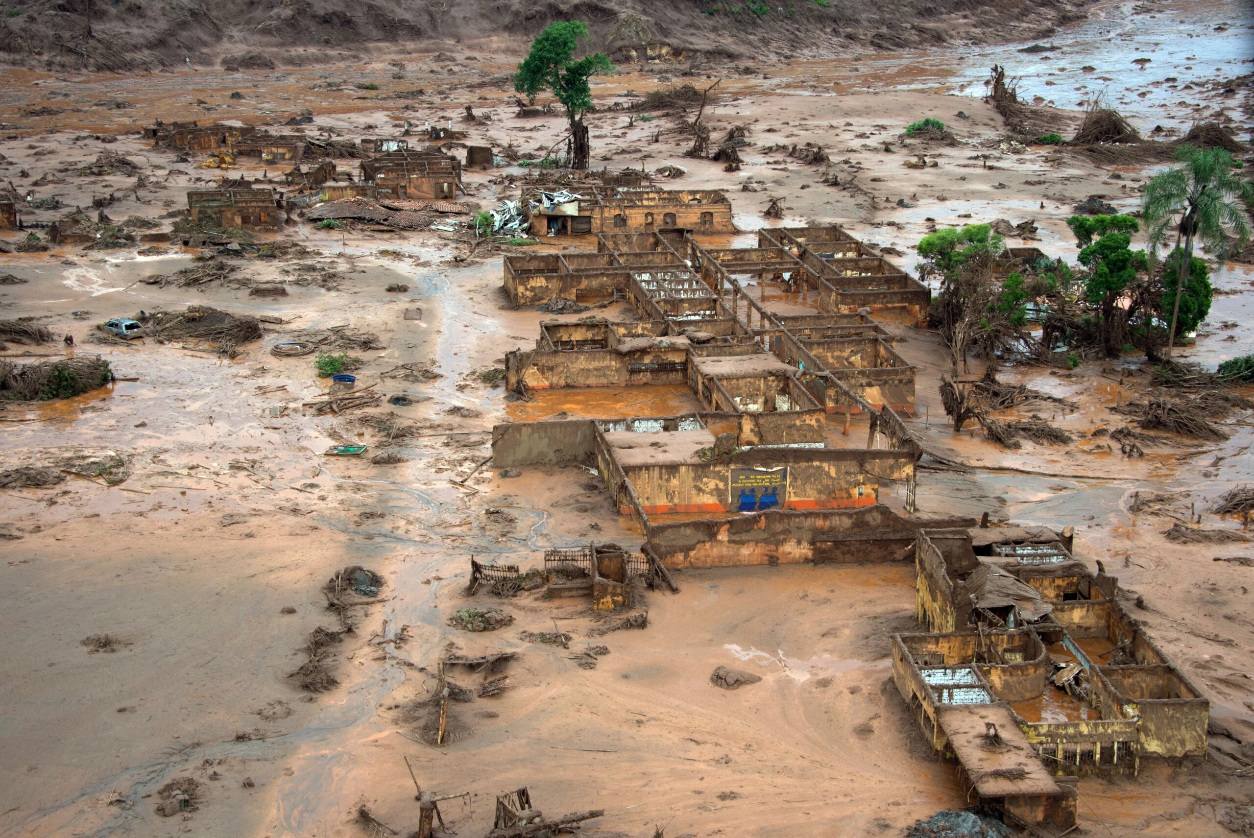 Aerial view of damages after a dam burst in the village of Bento Rodrigues, in Mariana, Minas Gerais state, Brazil on November 6, 2015. A dam burst at a mining waste site unleashing a deluge of thick, red toxic mud that smothered a village killing at least 17 people and injuring some 75. The mining company Samarco, which operates the site, is jointly owned by two mining giants, Vale of Brazil and BHP Billiton of Australia. AFP PHOTO /  CHRISTOPHE SIMON        (Photo credit should read CHRISTOPHE SIMON/AFP/Getty Images)