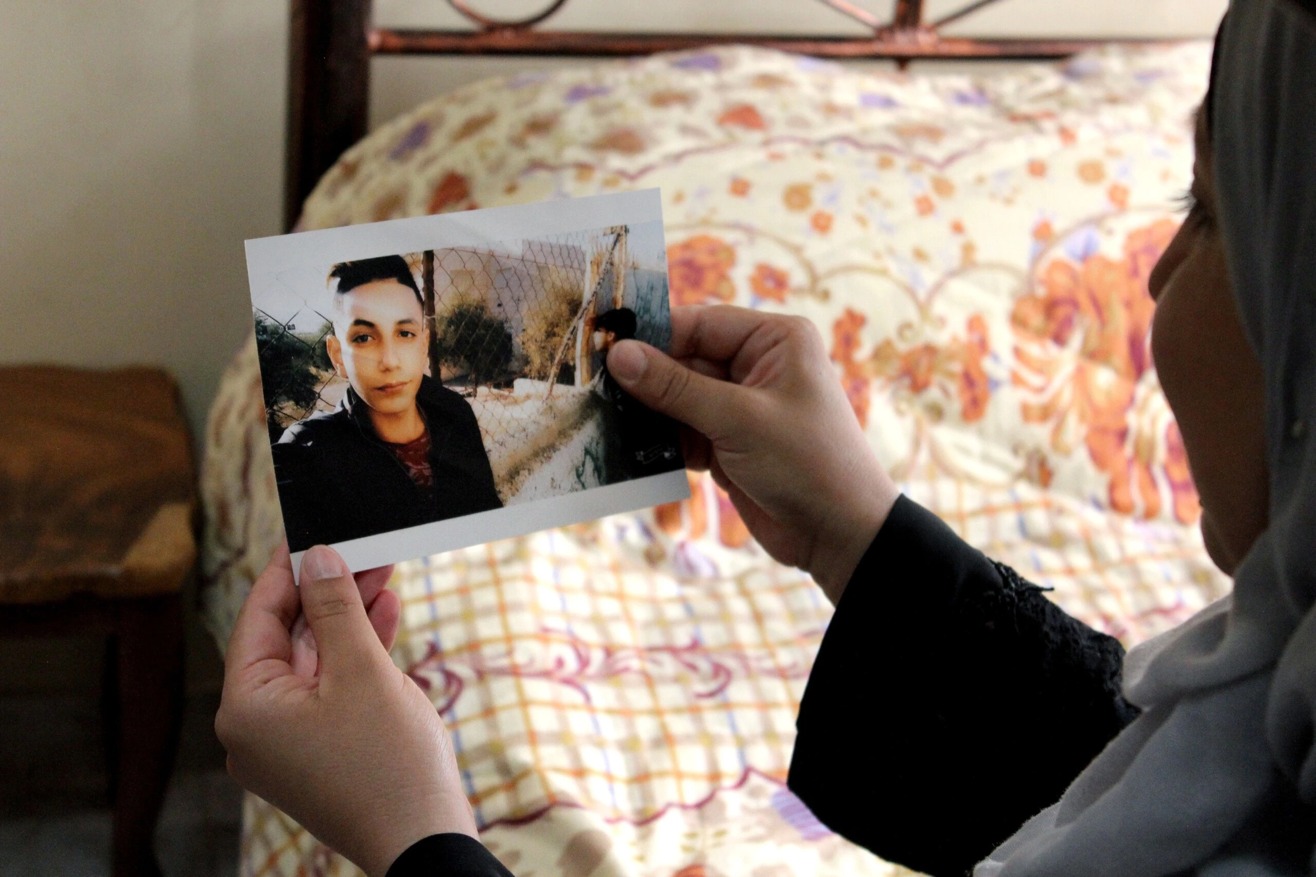 Nisreen Masaeed tem uma foto de seu filho de 16 anos, Mohammad, que atualmente está cumprindo 10 meses de prisão. Ela está dormindo na cama dele, retratada aqui, desde que ele foi para a prisão.