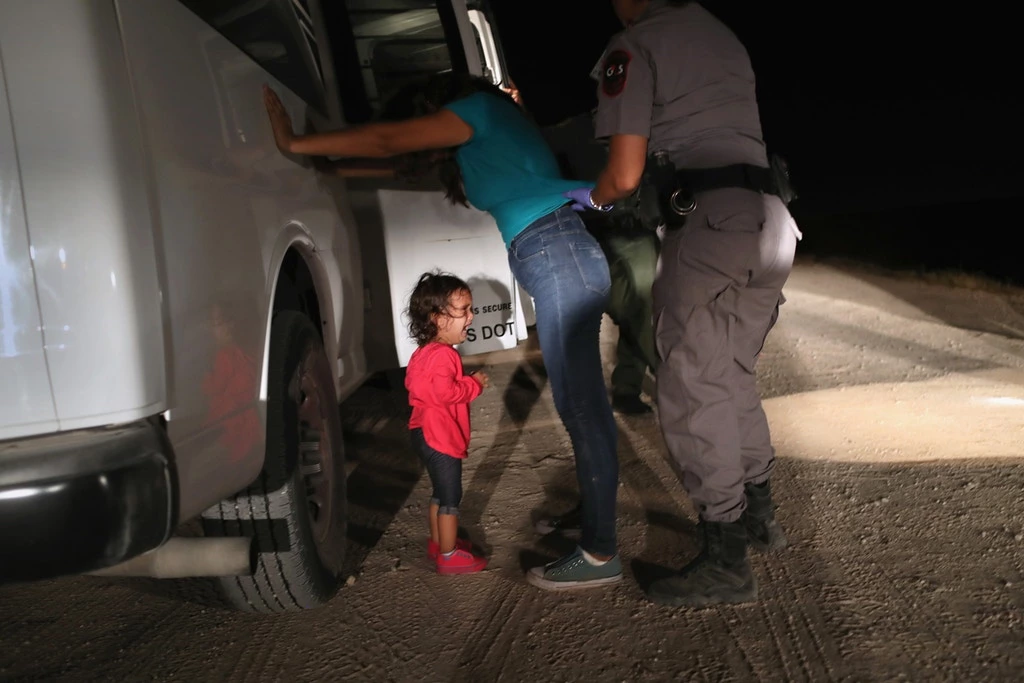 Uma criança hondurenha de 2 anos, solicitante de asilo, chora enquanto sua mãe é revistada e detida perto da fronteira entre os EUA e o México, em 12 de junho de 2018, em McAllen, no Texas.