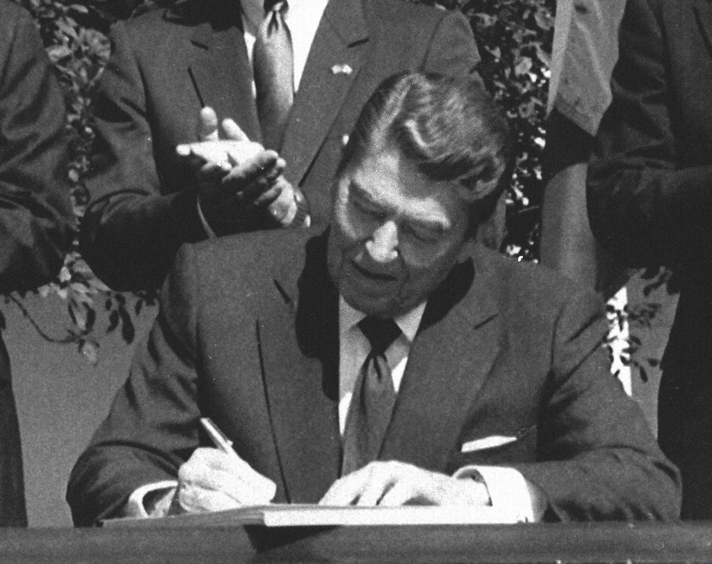 O presidente Ronald Reagan assina a legislação que implementa o tratado de livre-comércio entre os EUA e o Canadá durante cerimônia na Casa Branca, em 28 de setembro de 1988.