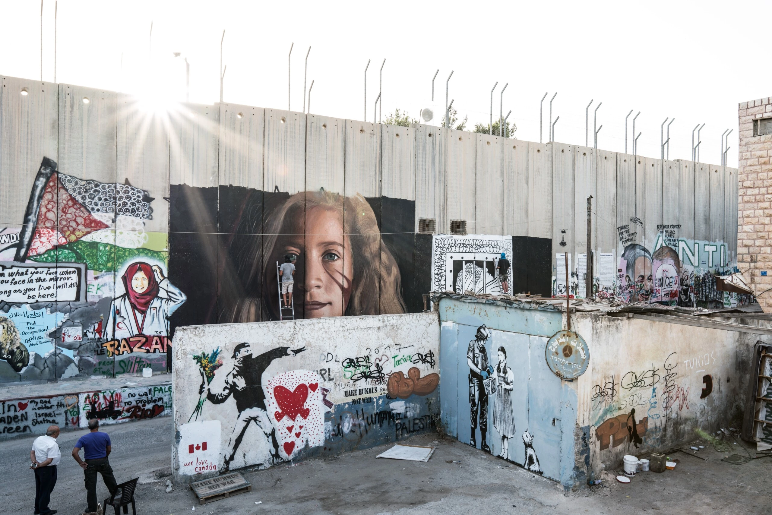 Um ativista italiano pinta um retrato de Ahed Tamimi em uma parte do muro de separação israelense em Belém.