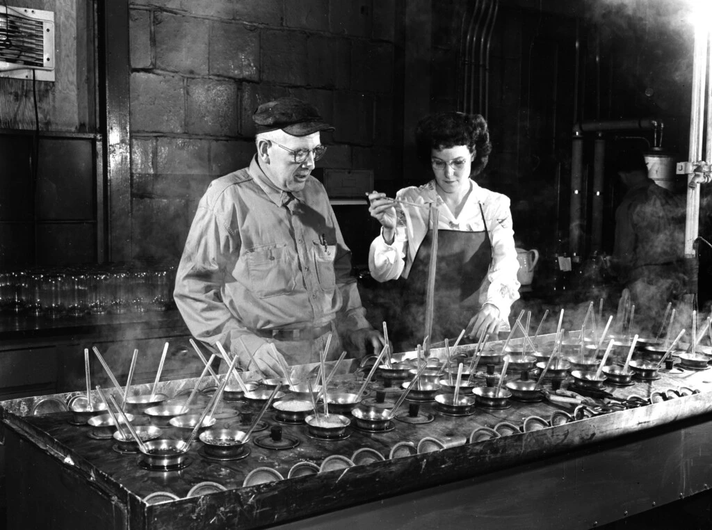 Um fabricante de corantes especializado no Departamento de Produtos Químicos Orgânicos Chambers Works da DuPont em Deepwater Point, Nova Jersey, acompanhado de um técnico de laboratório, verificando tonalidades de corantes nos anos 1950.