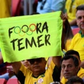 A man holds a sign against Brazil's acting President Michel Temer during the Rio 2016 Olympic Games First Round Group A men's football match Brazil vs South Africa, at the Mane Garrincha Stadium in Brasilia on August 4, 2016. / AFP / EVARISTO SA        (Photo credit should read EVARISTO SA/AFP/Getty Images)