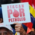 Manifestante segura uma placa onde se lê "Atacam por petróleo" durante um protesto em apoio a PDVSA em Caracas.