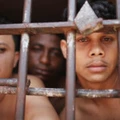 SAO LUIS, BRAZIL - JANUARY 27:  Inmates stand in their cell in the Pedrinhas Prison Complex, the largest penitentiary in Maranhao state, on January 27, 2015 in Sao Luis, Brazil. Previously one of the most violent prisons in Brazil, Pedrinhas has seen efforts from a new state administration, new prison officials and judiciary leaders from Maranhao which appear to have quelled some of the unrest within the complex. In 2013, nearly 60 inmates were killed within the complex, including three who were beheaded during rioting. Much of the violence stemmed from broken cells allowing inmates and gang rivals to mix in the patios and open spaces of the complex. Officials recently repaired and repopulated the cells allowing law enforcement access and decreasing violence among prisoners, according to officials. Other reforms include a policy of custody hearings and real-time camera feeds. According to officials there have been no prisoner on prisoner killings inside the complex in nearly four months. Critics believe overcrowding is one of the primary causes of rioting and violence in Brazil's prisons. Additionally, overcrowding has strengthened prison gangs which now span the country and contol certain peripheries of cities including Rio de Janeiro, Sao Paulo and Sao Luis. Brazil now has the fourth-largest prison population in the world behind the U.S., Russia and China. The population of those imprisoned had quadrupled in the past twenty years to around 550,000 and the country needs at least 200,000 new incarceration spaces to eliminate overcrowding. A vast increase in minor drug arrests, a dearth of legal advice for prisoners and a lack of political will for new prisons have contributed to the increases.  (Photo by Mario Tama/Getty Images)