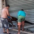 Men fix the broken shutter of their shop after burglars entered in Vila Velha, near Vitoria, eastern Brazil, on February 6, 2016. Brazil's government authorized deployment of troops Monday to the coastal city of Vitoria, which has been left at the mercy of criminals following a police strike. / AFP / Vinicius Moraes (Photo credit should read VINICIUS MORAES/AFP/Getty Images)
