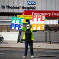 Uma mulher segura um cartaz com os dizeres "PPE" [EPI] diante do Hospital St. Thomas, em 7 de abril, em Londres.