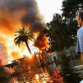 UNITED STATES - SEPTEMBER 04:  A man watches a house burn on Napolean St. as helicopters try to extinguish the fire by dropping water from above in Hurricane Katrina ravaged New Orleans. Because of the extensive flooding caused by the breaking of the city's levies, fire trucks were unable to reach burning homes and in some cases whole blocks burned to the ground.  (Photo by Craig Warga/NY Daily News Archive via Getty Images)