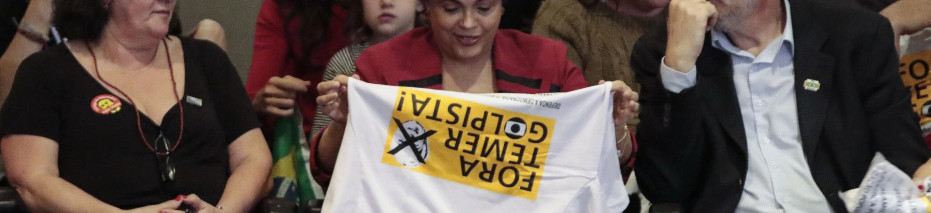 Brazilian suspended President Dilma Rousseff (C) holds a T-shirt reading "Temer out, pro-coup", referring to Brazilian acting President Michel Temer during a rally in Sao Paulo, Brazil on August 23, 2016.Brazil's suspended president Dilma Rousseff enters her final battle to win back power on Thursday, when senators open an impeachment trial expected to remove her from office for good. / AFP / Miguel Schincariol (Photo credit should read MIGUEL SCHINCARIOL/AFP/Getty Images)
