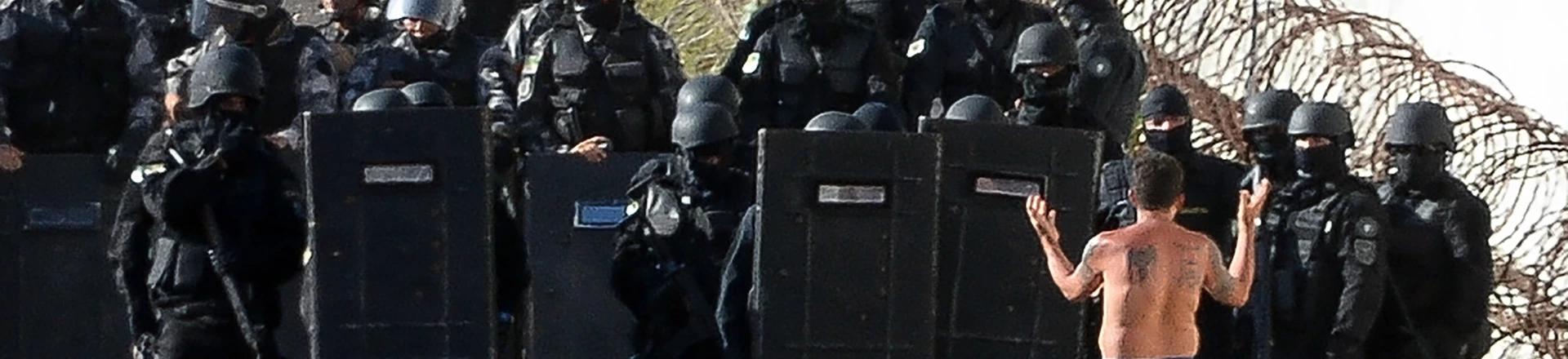 Riot police agents group and approach to negociate with an inmate's delegate (R) during a rebellion at the Alcacuz Penitentiary Center near Natal, Rio Grande do Norte state, northeastern Brazil on January 16, 2017.The latest in a string of brutal prison massacres involving suspected gang members in Brazil has killed 26 inmates, most of whom were beheaded. The bloodbath erupted Saturday night in the overcrowded Alcacuz prison in the northeastern state of Rio Grande do Norte. Similar violence at other jails in Brazil left around 100 inmates dead in early January. / AFP / ANDRESSA ANHOLETE (Photo credit should read ANDRESSA ANHOLETE/AFP/Getty Images) Riot police agents group and approach to negociate with an inmate's delegate (R) during a rebellion at the Alcacuz Penitentiary Center near Natal, Rio Grande do Norte state, northeastern Brazil on January 16, 2017.The latest in a string of brutal prison massacres involving suspected gang members in Brazil has killed 26 inmates, most of whom were beheaded. The bloodbath erupted Saturday night in the overcrowded Alcacuz prison in the northeastern state of Rio Grande do Norte. Similar violence at other jails in Brazil left around 100 inmates dead in early January. / AFP / ANDRESSA ANHOLETE (Photo credit should read ANDRESSA ANHOLETE/AFP/Getty Images)