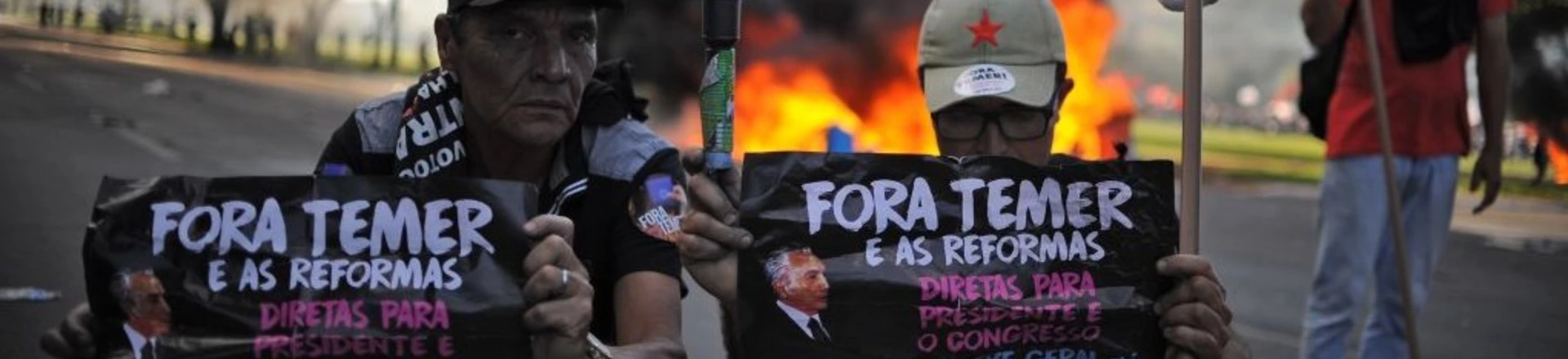 Demonstrators hold banners against Brazilian President Michel temer during clashes in the protest "Occupy Brasilia" against the labor and social security reforms of his government in Brasilia, on May 24, 2017. / AFP PHOTO / Andressa Anholete        (Photo credit should read ANDRESSA ANHOLETE/AFP/Getty Images)