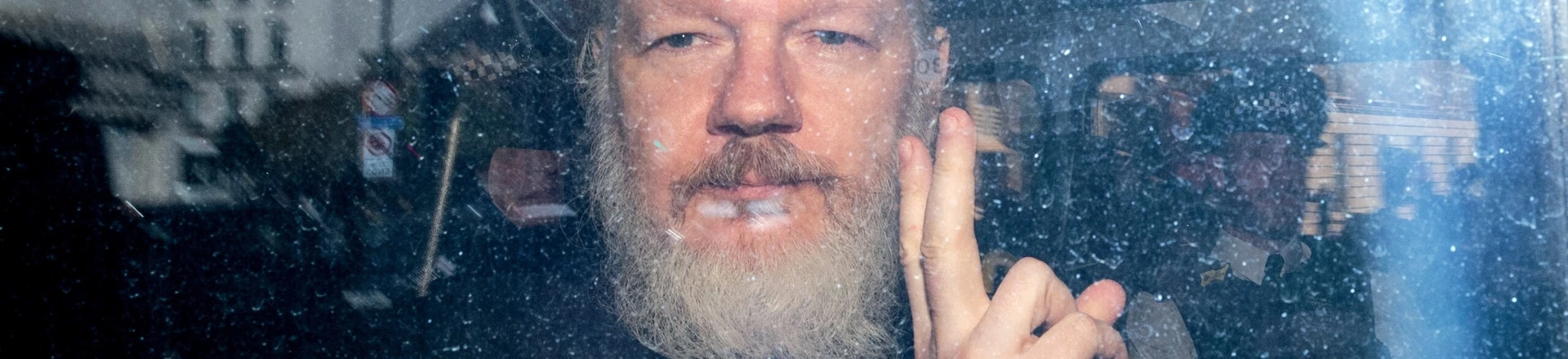 Julian Assange gesticula para a mídia de um veículo da polícia em sua chegada ao Tribunal Magistrados de Westminster, em 11 de abril de 2019 em Londres.
