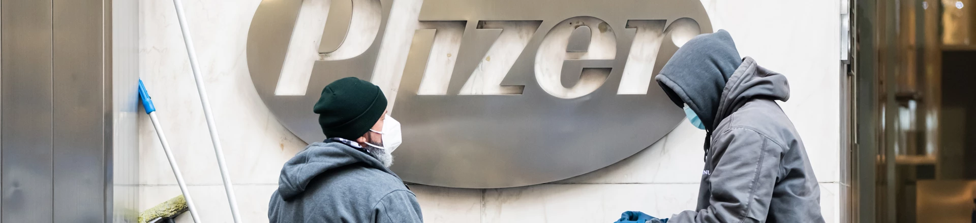Trabalhadores limpam o logotipo da Pfizer em 21 de dezembro de 2020, em Nova York.