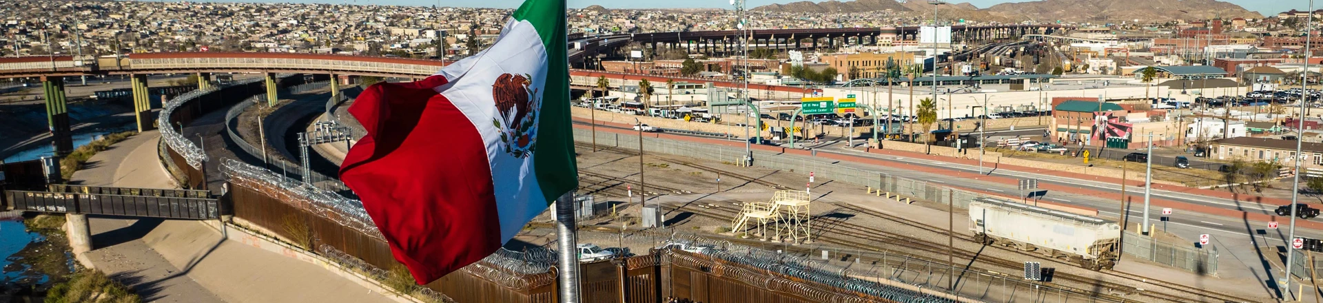 Vista aérea da bandeira do México sobre uma ponte internacional enquanto migrantes chegam à cerca da fronteira Estados Unidos para buscar asilo em 2022.