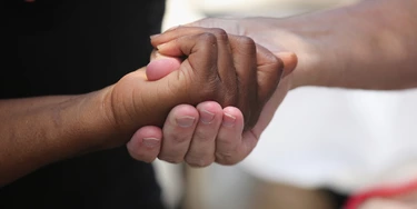 CHARLESTON, SC - JULY 17:  People clasp hands in prayer in front of the Emanuel African Methodist Episcopal  Church on July 17, 2015 in Charleston, South Carolina. Visitors from around the nation continue to pay their respects at a makeshift shrine at the church, in a show of faith and solidarity with "Mother Emanuel", as the church is known in Charleston. Nine people were allegedly murdered on June 17 by 21-year-old white supremacist Dylann Roof, who was captured by police in North Carolina the following day. He is scheduled to go to trial July 11, 2016.  (Photo by John Moore/Getty Images)