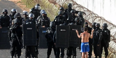 Riot police agents group and approach to negociate with an inmate's delegate (R) during a rebellion at the Alcacuz Penitentiary Center near Natal, Rio Grande do Norte state, northeastern Brazil on January 16, 2017.The latest in a string of brutal prison massacres involving suspected gang members in Brazil has killed 26 inmates, most of whom were beheaded. The bloodbath erupted Saturday night in the overcrowded Alcacuz prison in the northeastern state of Rio Grande do Norte. Similar violence at other jails in Brazil left around 100 inmates dead in early January. / AFP / ANDRESSA ANHOLETE (Photo credit should read ANDRESSA ANHOLETE/AFP/Getty Images)