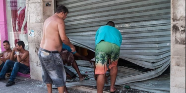 Men fix the broken shutter of their shop after burglars entered in Vila Velha, near Vitoria, eastern Brazil, on February 6, 2016. Brazil's government authorized deployment of troops Monday to the coastal city of Vitoria, which has been left at the mercy of criminals following a police strike. / AFP / Vinicius Moraes (Photo credit should read VINICIUS MORAES/AFP/Getty Images)