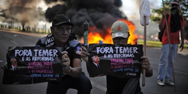 Demonstrators hold banners against Brazilian President Michel temer during clashes in the protest "Occupy Brasilia" against the labor and social security reforms of his government in Brasilia, on May 24, 2017. / AFP PHOTO / Andressa Anholete (Photo credit should read ANDRESSA ANHOLETE/AFP/Getty Images) Demonstrators hold banners against Brazilian President Michel temer during clashes in the protest "Occupy Brasilia" against the labor and social security reforms of his government in Brasilia, on May 24, 2017. / AFP PHOTO / Andressa Anholete (Photo credit should read ANDRESSA ANHOLETE/AFP/Getty Images)