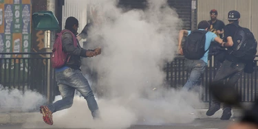 Demonstrators run amid a cloud of tear gas during a protest organized by the Homeless Workers Movement, in Sao Paulo, Brazil, Wednesday, June 1, 2016. The movement organized the protest against acting President Michel Temer and in support of suspended President Dilma Rousseff.  (AP Photo/Andre Penner)