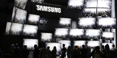 FILE - In this Thursday, Jan. 8, 2015, file photo, attendees watch a presentation at the Samsung booth at the International CES, in Las Vegas. For years, TV makers have focused on making pictures sharper by squeezing more pixels onto screens, but now their attention is shifting to improving the way sets display color, with a newish technology called HDR taking center stage. (AP Photo/Jae C. Hong, File) FILE - In this Thursday, Jan. 8, 2015, file photo, attendees watch a presentation at the Samsung booth at the International CES, in Las Vegas. For years, TV makers have focused on making pictures sharper by squeezing more pixels onto screens, but now their attention is shifting to improving the way sets display color, with a newish technology called HDR taking center stage. (AP Photo/Jae C. Hong, File)