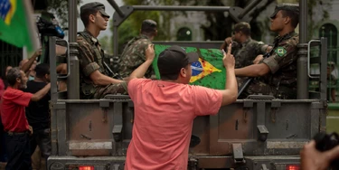 Friends and relatives of Brazilian musician Evaldo dos Santos Rosa, who was killed by an army unit when it shot at his car by mistake, hold Brazilian national flags stained in red -as blood- during a protest at Vila Militar neighborhood in Rio de Janeiro, Brazil on April 10, 2019. - Brazilian military authorities detained 10 soldiers who were part of a unit that shot over 80 times at a vehicle in Guadalupe neighborhood, Rio de Janeiro, killing a man and injuring two others Sunday. (Photo by Mauro Pimentel / AFP) (Photo credit should read MAURO PIMENTEL/AFP via Getty Images) Friends and relatives of Brazilian musician Evaldo dos Santos Rosa, who was killed by an army unit when it shot at his car by mistake, hold Brazilian national flags stained in red -as blood- during a protest at Vila Militar neighborhood in Rio de Janeiro, Brazil on April 10, 2019. - Brazilian military authorities detained 10 soldiers who were part of a unit that shot over 80 times at a vehicle in Guadalupe neighborhood, Rio de Janeiro, killing a man and injuring two others Sunday. (Photo by Mauro Pimentel / AFP) (Photo credit should read MAURO PIMENTEL/AFP via Getty Images)