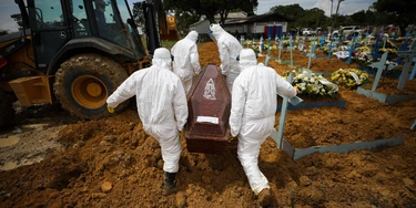 15 January 2021, Brazil, Manaus: Cemetery workers in protective suits carry the coffin of a person who died of Covid-19 at Nossa Senhora Aparecida Cemetery. In the state of Amazonas alone, 223,360 Covid-19 cases have been confirmed. Manaus, the state capital, last registered the most Covid-19-related hospitalizations since April 2020, and the local health system had collapsed. The Brazilian Air Force had to deliver oxygen to the region. Photo: Lucas Silva/dpa (Photo by Lucas Silva/picture alliance via Getty Images) 15 January 2021, Brazil, Manaus: Cemetery workers in protective suits carry the coffin of a person who died of Covid-19 at Nossa Senhora Aparecida Cemetery. In the state of Amazonas alone, 223,360 Covid-19 cases have been confirmed. Manaus, the state capital, last registered the most Covid-19-related hospitalizations since April 2020, and the local health system had collapsed. The Brazilian Air Force had to deliver oxygen to the region. Photo: Lucas Silva/dpa (Photo by Lucas Silva/picture alliance via Getty Images)