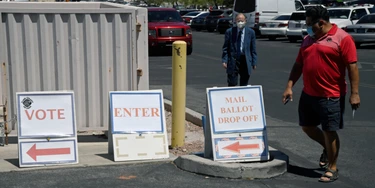 Pessoas caminham seguindo os cartazes enquanto se dirigem ao Departamento Eleitoral do Condado de Clark, que serve como ponto de votação principal nas eleições e como centro de votação presencial em meio à pandemia de coronavírus em 9 de junho de 2020, em North Las Vegas, Nevada.
