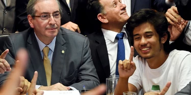 Kim Kataguiri (R), leader of the Free Brazil Movement (MBL), meets with Brazilian Lower House President Eduardo Cunha in Brasilia, Brazil on May 27, 2015. Kataguiri, a 19-year-old college drop out, is the face of MBL, a growing force which seeks to harness some of the energy of the 2013 protest movement which brought more than a million onto the streets. AFP PHOTO/EVARISTO SA        (Photo credit should read EVARISTO SA/AFP/Getty Images)