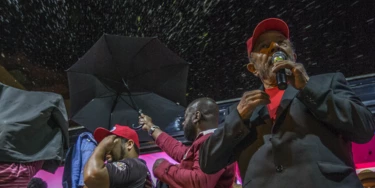 Assessores seguram guarda-chuvas para evitar que Lula seja atingido por ovos. Assessores seguram guarda-chuvas para evitar que Lula seja atingido por ovos.