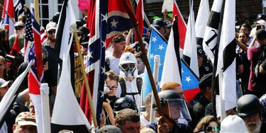 White nationalist demonstrators walk into the entrance of Lee Park surrounded by counter demonstrators in Charlottesville, Va., Saturday, Aug. 12, 2017. Gov. Terry McAuliffe declared a state of emergency and police dressed in riot gear ordered people to disperse after chaotic violent clashes between white nationalists and counter protestors. (AP Photo/Steve Helber)
