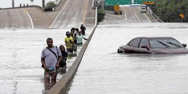 Evacuees wade down a flooded section of Interstate 610 as floodwaters from Tropical Storm Harvey rise Sunday, Aug. 27, 2017, in Houston. The remnants of Hurricane Harvey sent devastating floods pouring into Houston Sunday as rising water chased thousands of people to rooftops or higher ground. (AP Photo/David J. Phillip)